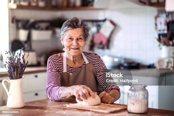 Photo libre de droit de Une Femme Senior Pétrir La Pâte Dans La Cuisine À La Maison banque d'images et plus d'images libres de droit de Femmes seniors