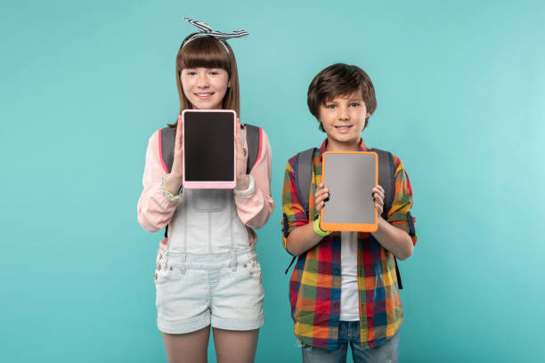 istock Happy kids showing their tablets 988253310