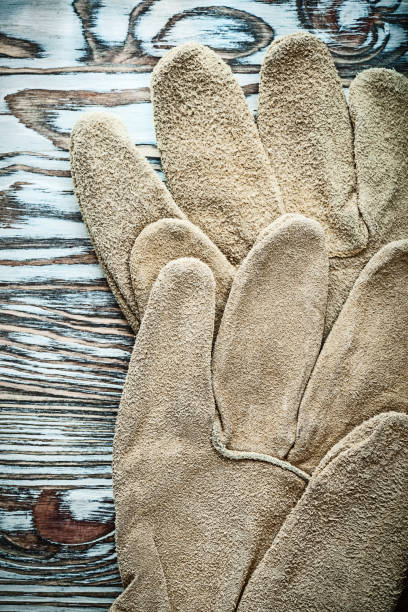 istock Pair of leather protective gloves on wooden board 988274272