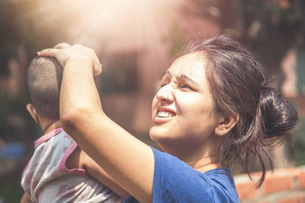 Indian kid and mother standing outside in sunlight during hot summer season
