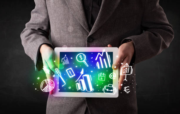 istock Young person holding tablet with graph and chart symbols 988286634