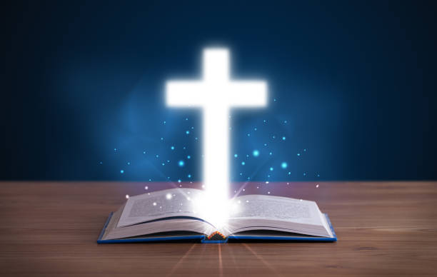 istock Open holy bible with glowing cross in the middle 988287158