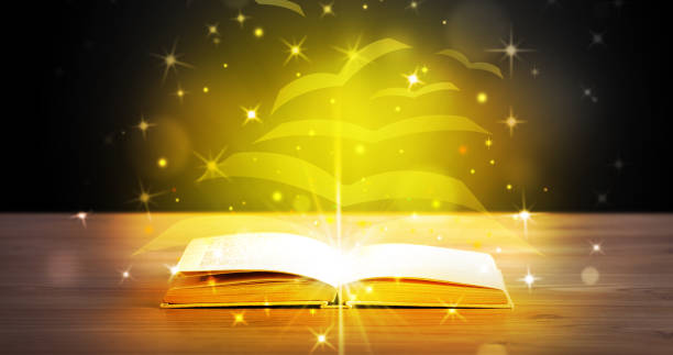 istock Open book with golden glow flying paper pages 988287216