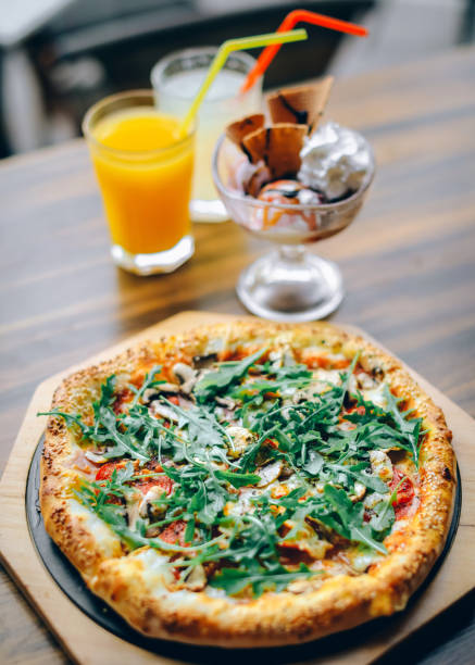 istock Pizza served on wooden plate with drinks 988293368