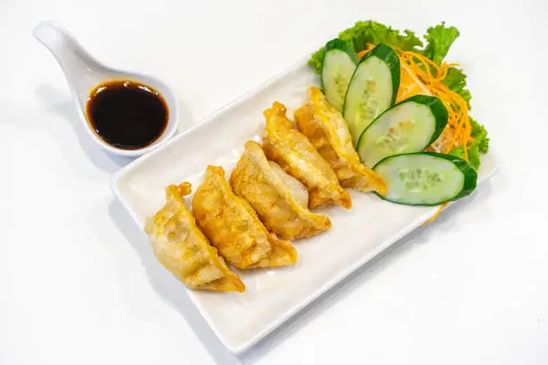 Photo of Gyoza. Japanese pan-fried dumpling served with vinegar or Japanese soy sauce, cucumber, carrot and vegetable. Gyoza are popular weeknight meal as well as a great appetizer for your dinner.