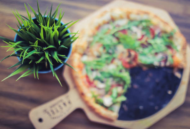 Decorative plant on restaurant table  and blurry pizza in background. Background concept.