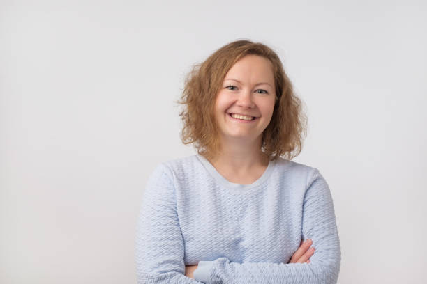 istock Smiling european lady in blue sweater looking at camera, isolated on gray background. 988308564