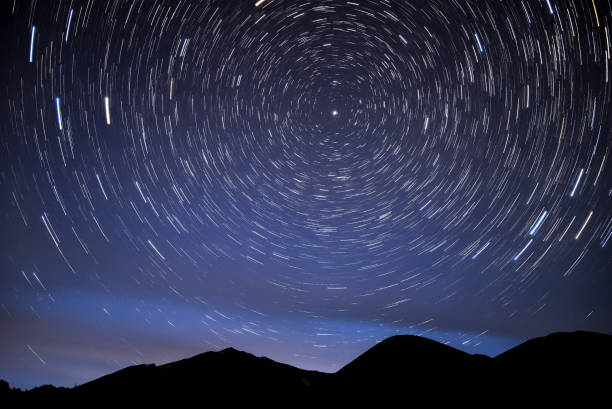 mountains star tracks sky glow Bright traces of stars revolving around the polar star, in the form of circular tracks and glow in the night sky against the background of the mountains north star stock pictures, royalty-free photos & images