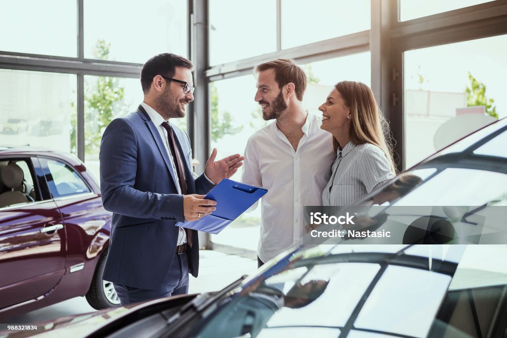 Young couple buying a car Car salesman making a sale Car Stock Photo