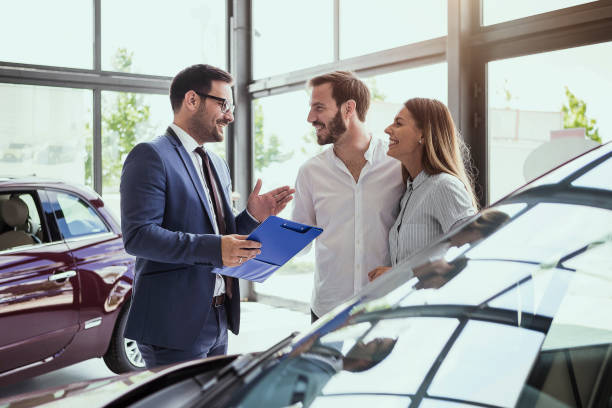 Salesperson stands with Clients in car dealership in saskatoon