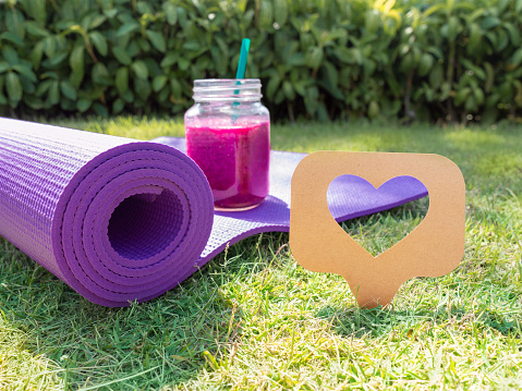 Like us icon, dragon fruit purple milk shake and yoga mat on grass lawn like concept copy space