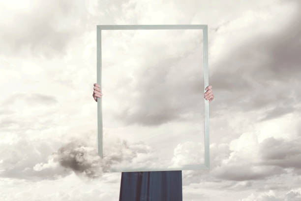 surreal moment of a woman hiding behind a picture of clouds equal to the landscape - imagination fantasy invisible women imagens e fotografias de stock