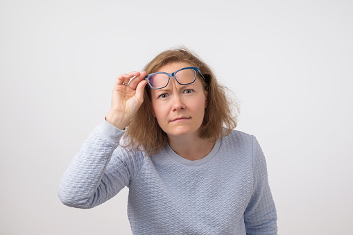 Mature european woman looking carefully not believing her eyes. She is moving her glasses up. What, really surprised concept