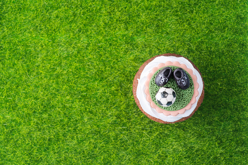 Beautiful fresh Cupcake in a football style on a green lawn - top view