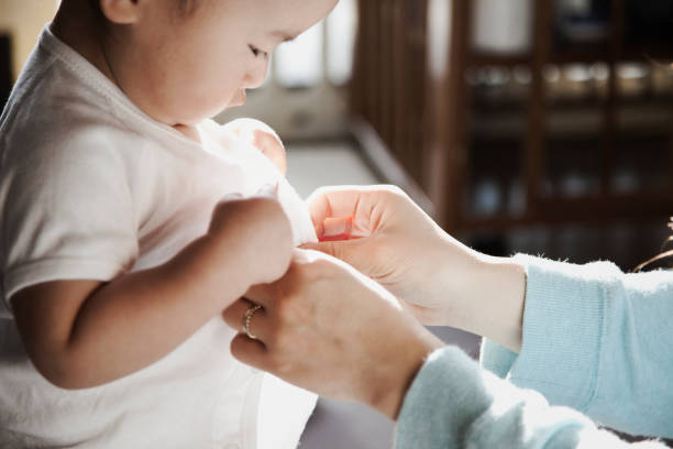 Mother helping her baby boy changing his clothes