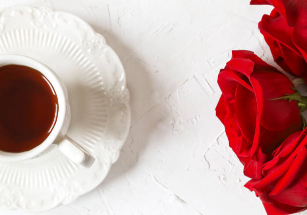 istock Cup of tea and red roses, top view 988372904