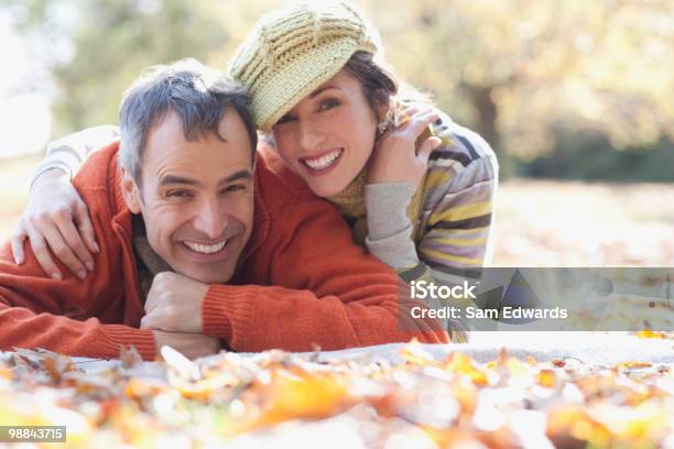 Sonriente Pareja Que Descansan En Hojas Otoñales Foto de stock y más banco de imágenes de 30-34 años - 30-34 años, 30-39 años, 45-49 años