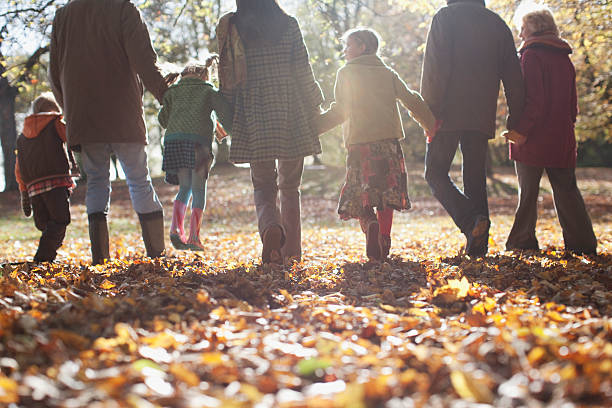 familia sosteniendo las manos y caminar al aire libre - coat grandfather grandchild granddaughter fotografías e imágenes de stock