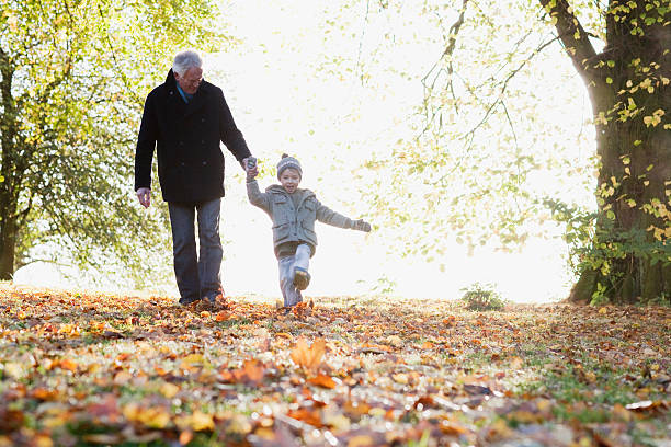 Grandfather walking outdoors with grandson in autumn  kicking photos stock pictures, royalty-free photos & images