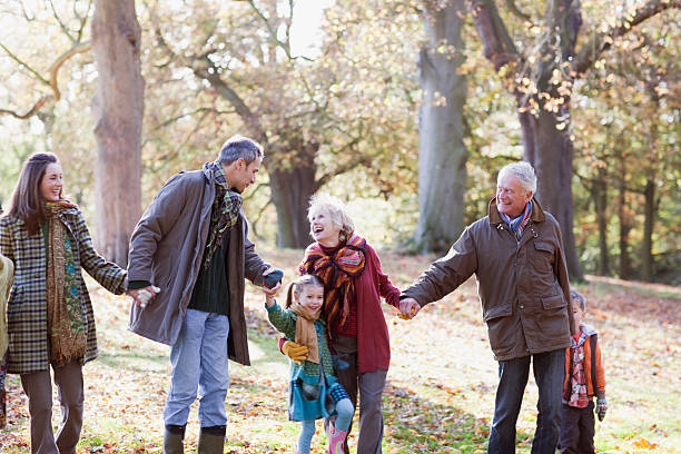 familia sosteniendo las manos y caminar en park - coat grandfather grandchild granddaughter fotografías e imágenes de stock