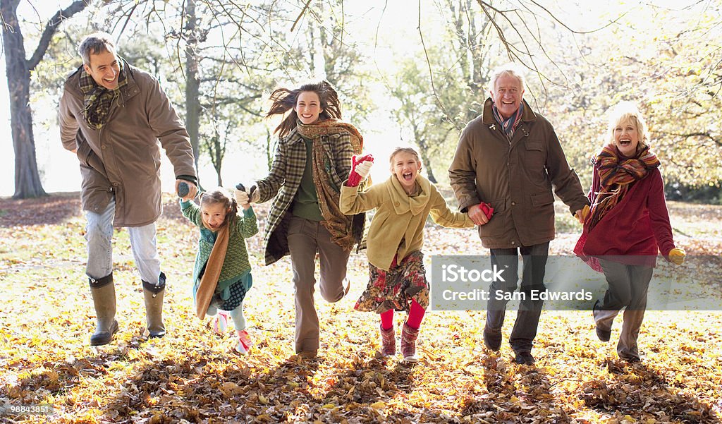 Extended family running in park in autumn  Family Stock Photo