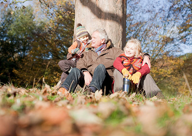 grands-parents et petit-fils penchant contre un arbre - tree grass family human relationship family photos et images de collection