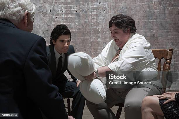Group Of Businesspeople In Warehouse Stock Photo - Download Image Now - Meeting, Overweight, Sitting