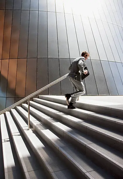 Photo of Businessman rushing up steps outdoors