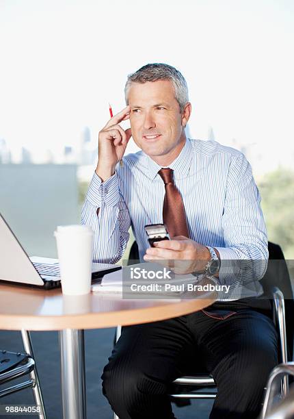 Photo libre de droit de Homme Daffaires En Tenant Le Téléphone Portable Au Café banque d'images et plus d'images libres de droit de 40-44 ans