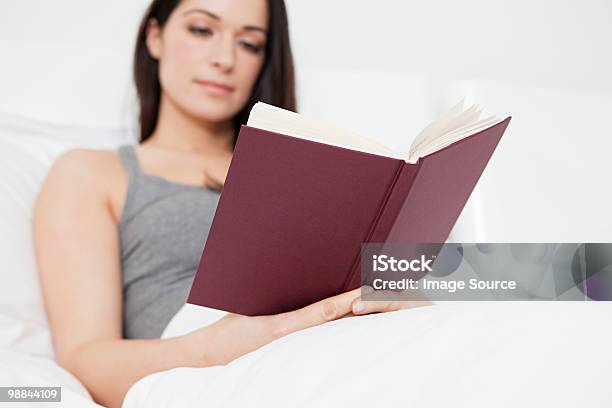 Mujer Joven Lectura En La Cama Foto de stock y más banco de imágenes de Adulto - Adulto, Adulto joven, Cabello castaño