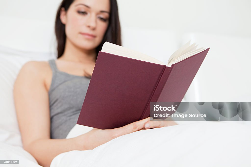 Молодая женщина, чтение в постели - Стоковые фото В помещении роялти-фри