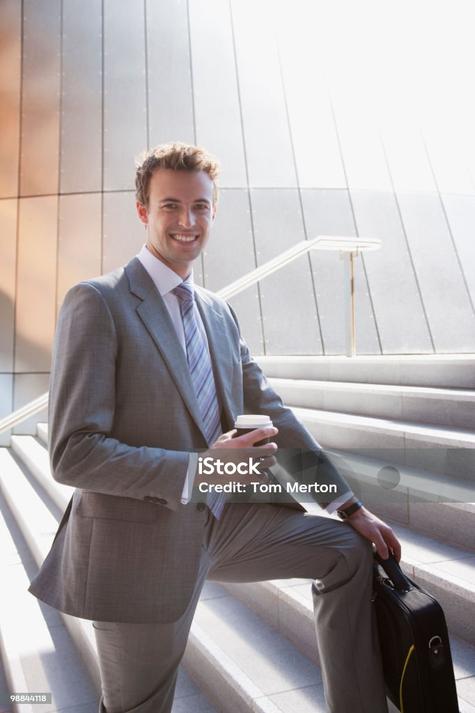 Uomo d'affari tenendo caffè all'aperto a pochi passi - Foto stock royalty-free di Uomini