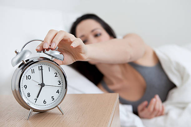 Young woman reaching for alarm clock  alarm clock stock pictures, royalty-free photos & images