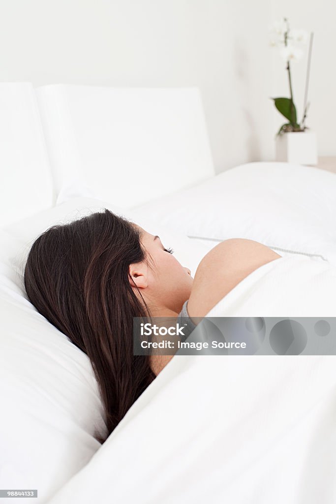 Joven mujer durmiendo en la cama - Foto de stock de Acostado libre de derechos