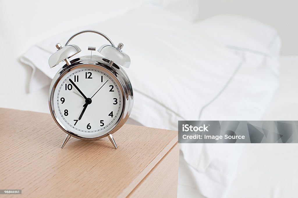 目覚まし時計でベッド - ベッドサイドテーブルのロイヤリティフリーストックフォト