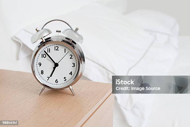 Alarm Clock By Bed — стоковые фотографии и другие картинки Будильник - Будильник, Прикроватная тумбочка, Без людей