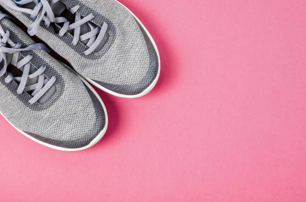 istock Grey female sneakers on pink background. 988475052