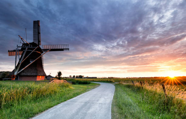 istock sunset over road and windmill in summer, Netherlands 988478046