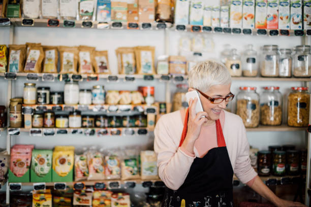 istock Mature woman using mobile phone while working at the shop 988478550