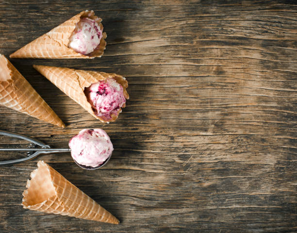 istock Raspberry vanilla ice cream scoop in a spoon with waffles cones on wooden background 988483678