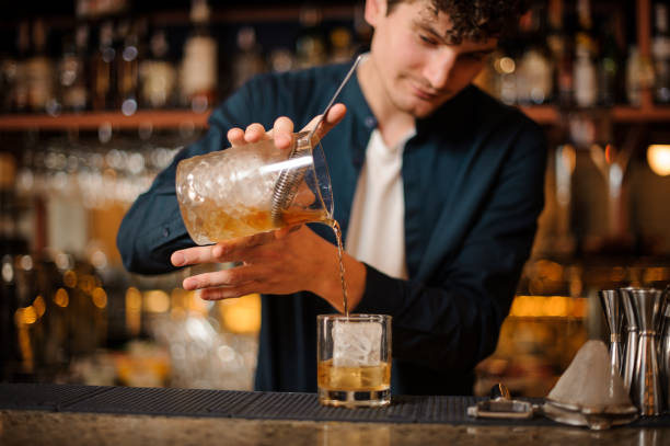 istock barman prepares an Old Fashioned alcoholic cocktail, adding whiskey to the ice 988485550