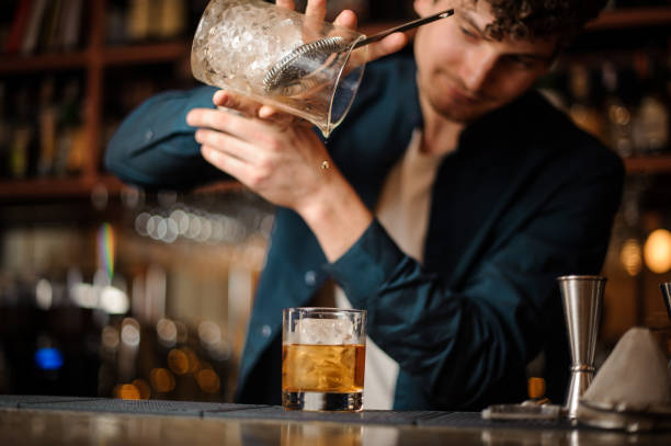 istock barman finishes preparing an alcoholic cocktail Old Fashioned 988489064