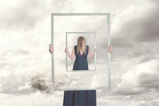 istock surreal image of a woman holding a frame that reflects herself 988489162