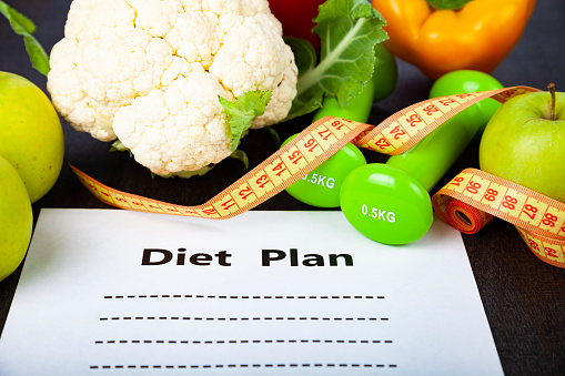 Food and sheet of paper with a diet plan on a dark wooden background. Concept of diet and healthy lifestyle.