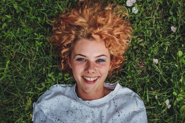 istock Beautiful woman lying down in the grass 988490714