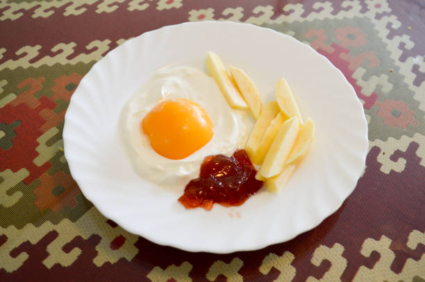This is a foto of a special breakfast. It's a fried egg made of yoghurt and peach, apple fries and strawberry jam ketchup.