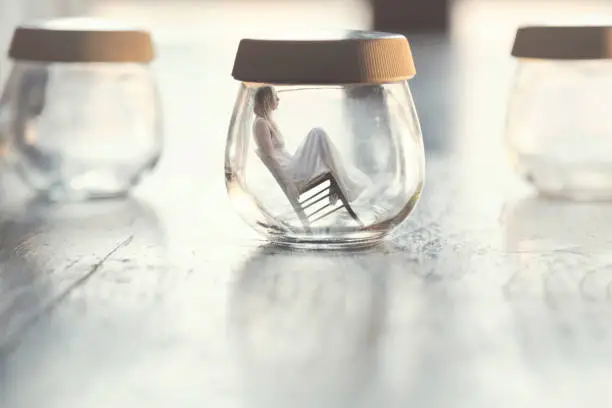 Photo of surreal moment of a tiny woman sitting on a chair inside a glass vase in the table at home