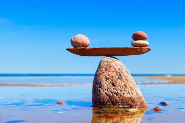 Symbolic scales made of stones on the sea background. Concept of harmony and balance. Pros and cons, work - life concept