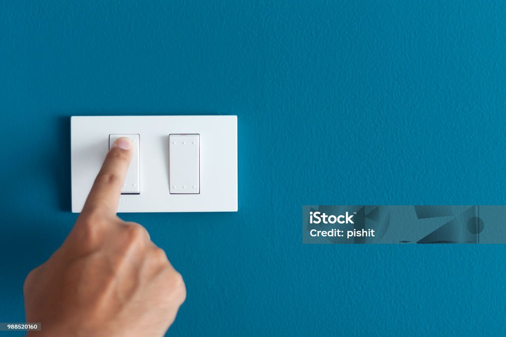 Un dedo encender interruptor de iluminación en áspero en pared azul oscurezca. - Foto de stock de Interruptor libre de derechos