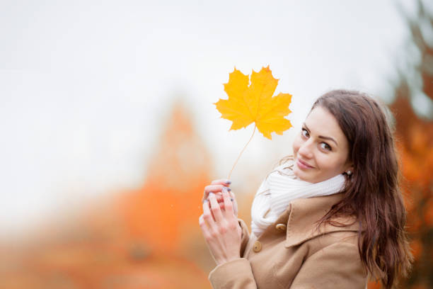 istock Young woman holding autumn yellow maple leave 988531958